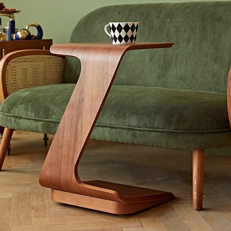 Hero Image 2: Curved walnut side table next to green velvet chair